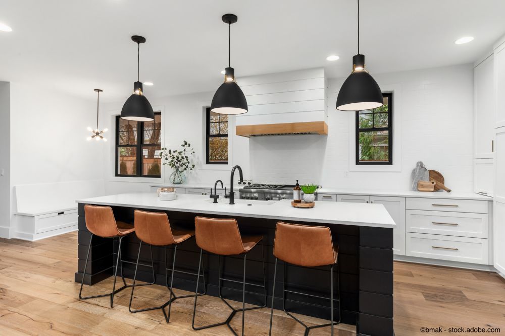 Schöne weiße Küche mit dunklen Akzenten in einem neuen modernen Luxushaus im Landhausstil