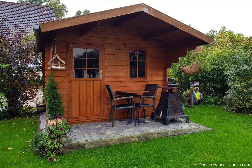 Holzgartenhaus mit Satteldach, kleiner Terrasse und Sitzgarnitur im gepflegten Garten