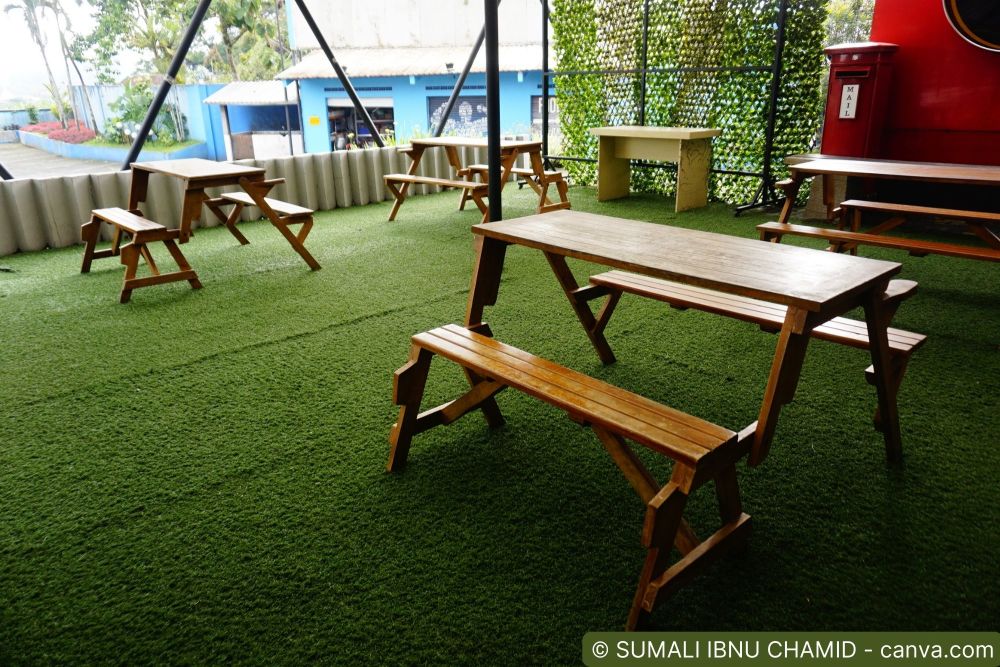 Verlegter Kunstrasen auf einer Terrasse mit Holztischen und Bänken