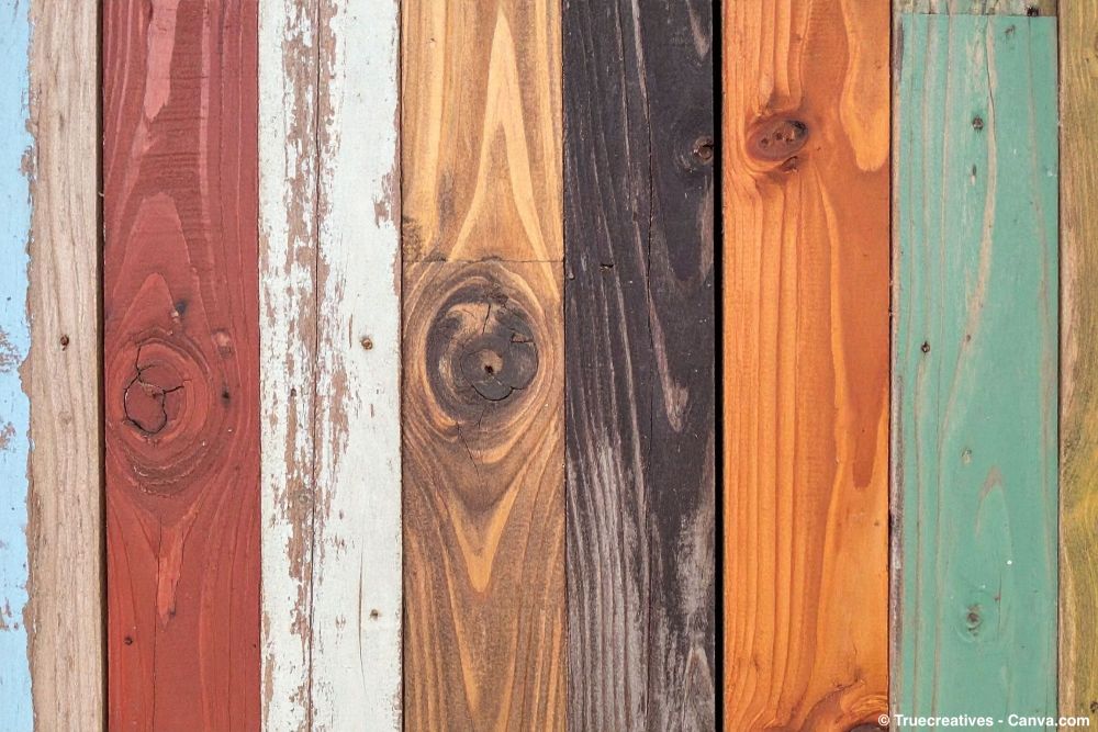 Bunte Holzbohlen mit unterschiedlichen Anstrichen und Lasuren, teils verwittert und abgeblättert