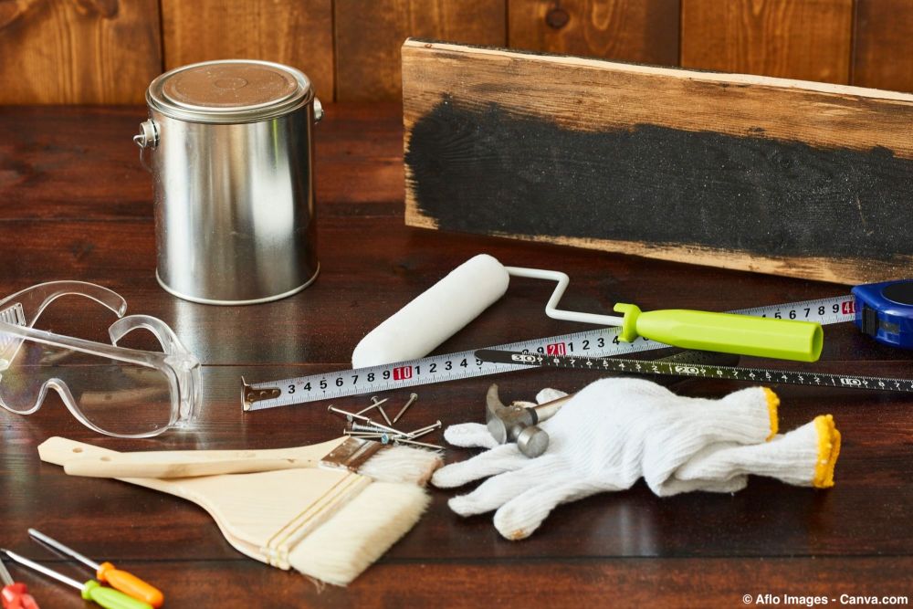 Werkzeugset zum Holzstreichen mit Lackdose, Roller, Pinsel und Holzbrett.