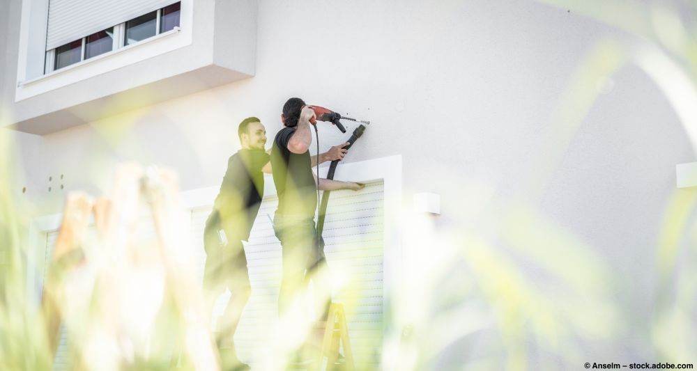 Handwerker bohren Löcher in die Hauswand zur Befestigung einer Markise