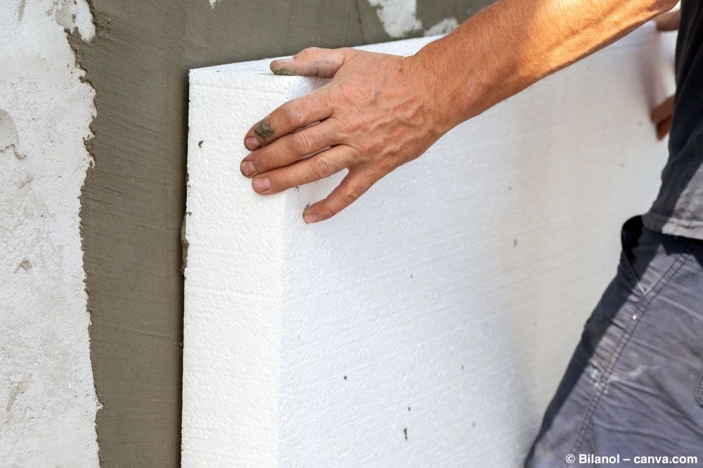 Handwerker setzt Dämmplatte an die Fassade