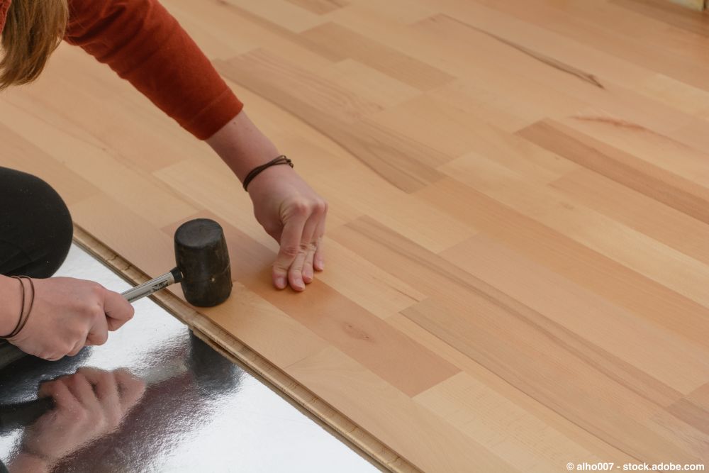 Verlegen von Parkettboden mit Gummihammer und Trittschalldämmung auf dem Untergrund
