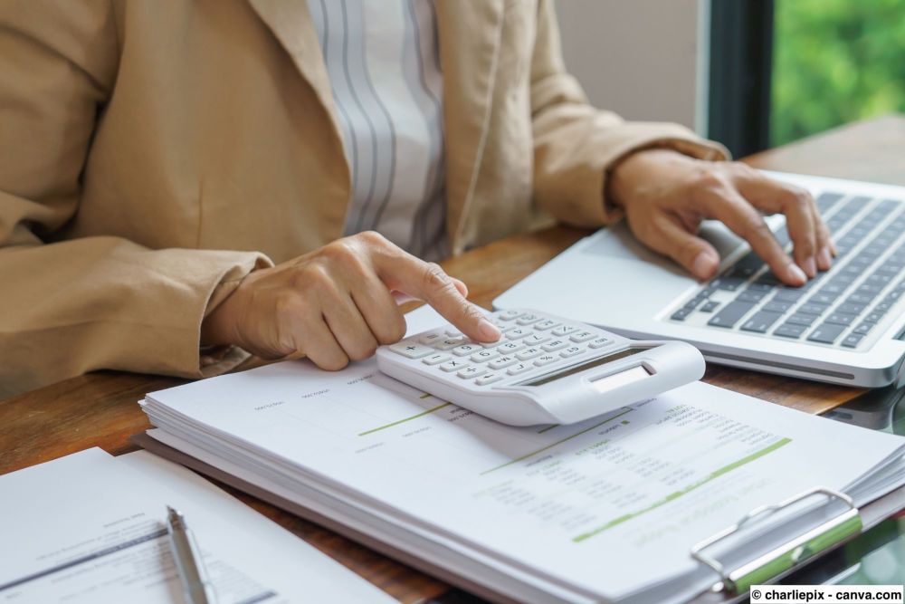 Person berechnet mit Taschenrechner, wie viel Wandfarbe für einen Raum benötigt wird.