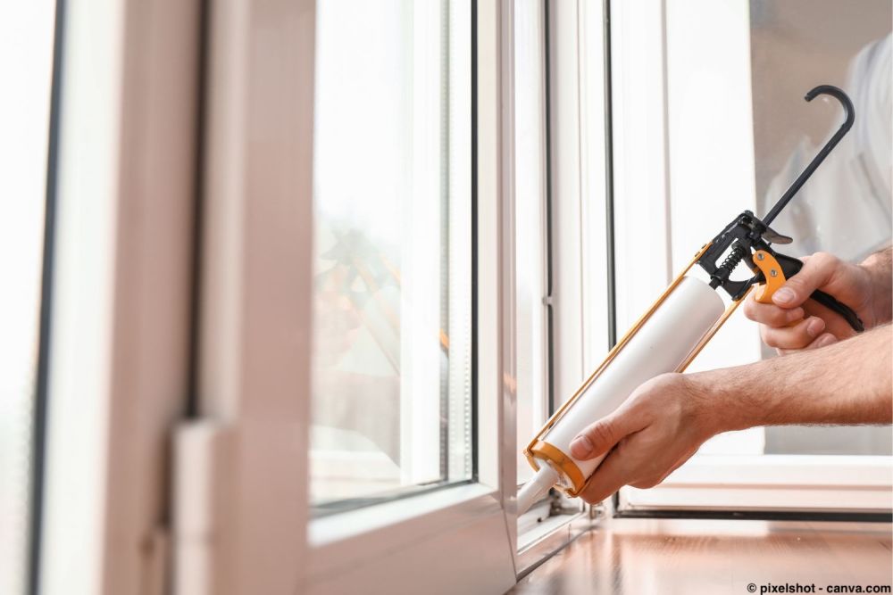 Handwerker dichtet ein Fenster mit einer Kartuschenpistole und Silikon ab.