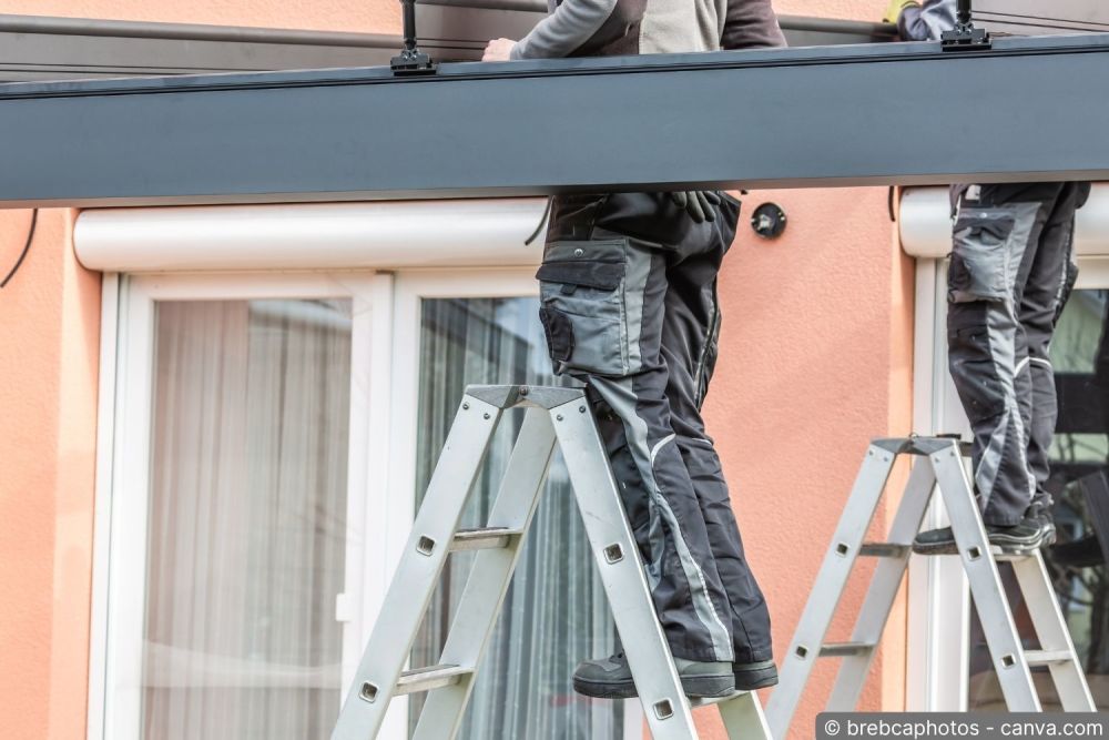 Storenmonteur montiert eine neue Sonnenstore von einem Gerüst aus
