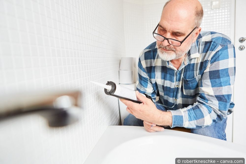 Handwerker erneuert die Silikonfuge an einer Badewanne