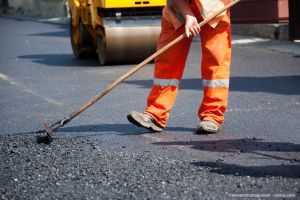 Fachmann verlegt frischen Asphalt auf einer Strasse