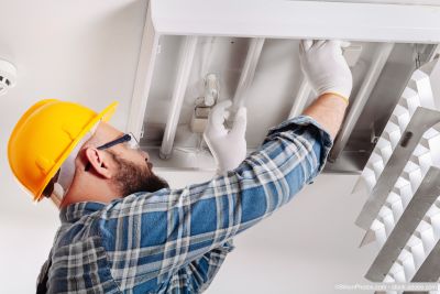 Elektriker bringt Lampenstrahler an der Decke an