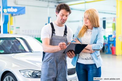 Kfz-Mechaniker übergibt Auto nach Inspektion an Kundin