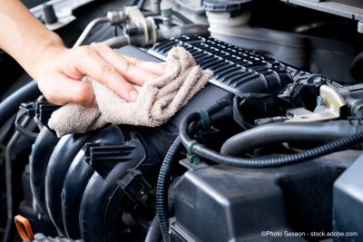 Mann wäscht Automotor mit einem Lappen