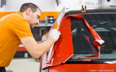 Mann foliert Auto mit roter Folie