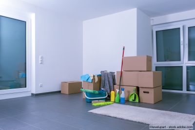 Helle, leere Luxuswohnung mit Kartons und Putzmittel auf schwarzem Fliesenboden