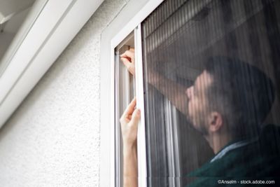 Freundlicher Handwerker montiert Fliegenschutzgitter bei einem Kunden zu Hause