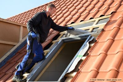 Dachdecker baut Dachfenster von "Velux" auf dem Bau in rote Dachziegel Dächer ein