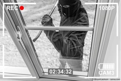 CCTV-Aufnahme eines Einbrechers, der durch ein Fenster in ein Haus eindringt