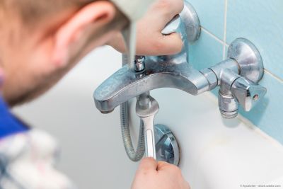 Sanitär beim Reparieren eines Wasserhahns mit Werkzeugschlüssel