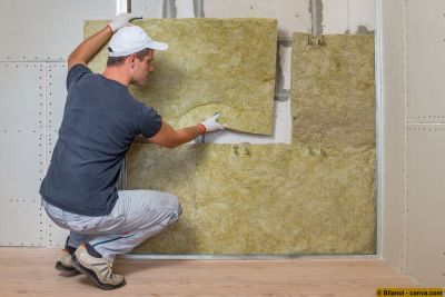 Arbeiter isoliert eine Raumwand mit Mineralwolle