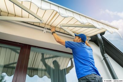 Handwerker montiert eine Markise an der Hauswand über einer Terrassentür