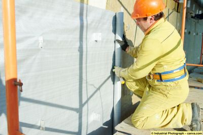 Bauarbeiter montiert eine diffusionsoffene Fassadenbahn