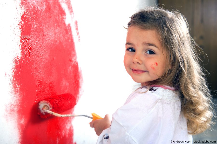 Kinderzimmer wird von kleinem Mädchen in roter Wandfarbe gestrichen