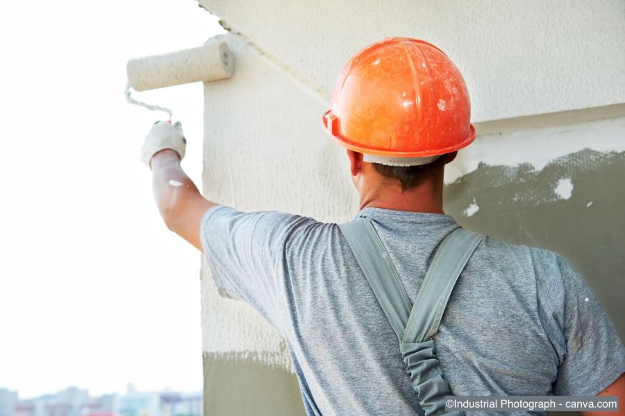 Fachmann streicht Ecke einer Hausfassade