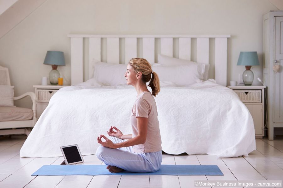 Frau meditiert im Schlafzimmer