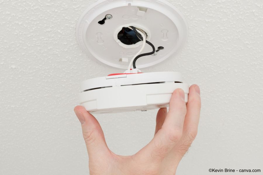 Drahtgebundener Rauchmelder wird von der Decke genommen