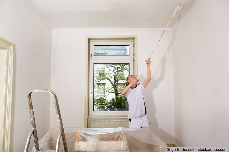 Maler streicht Wände und Decke in Weiss