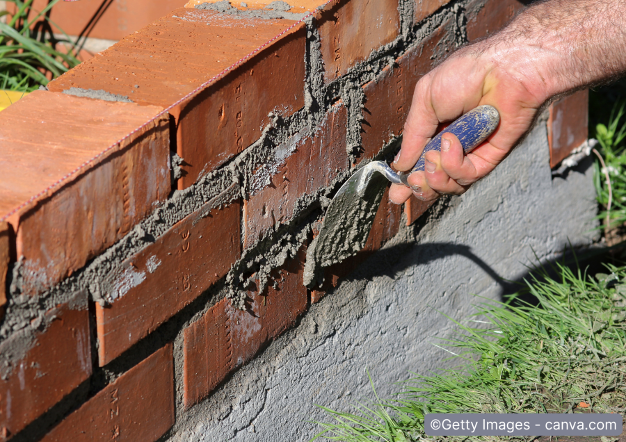 Bau-einer-Ziegelsteinmauer-mit-Kelle-und-Moertel