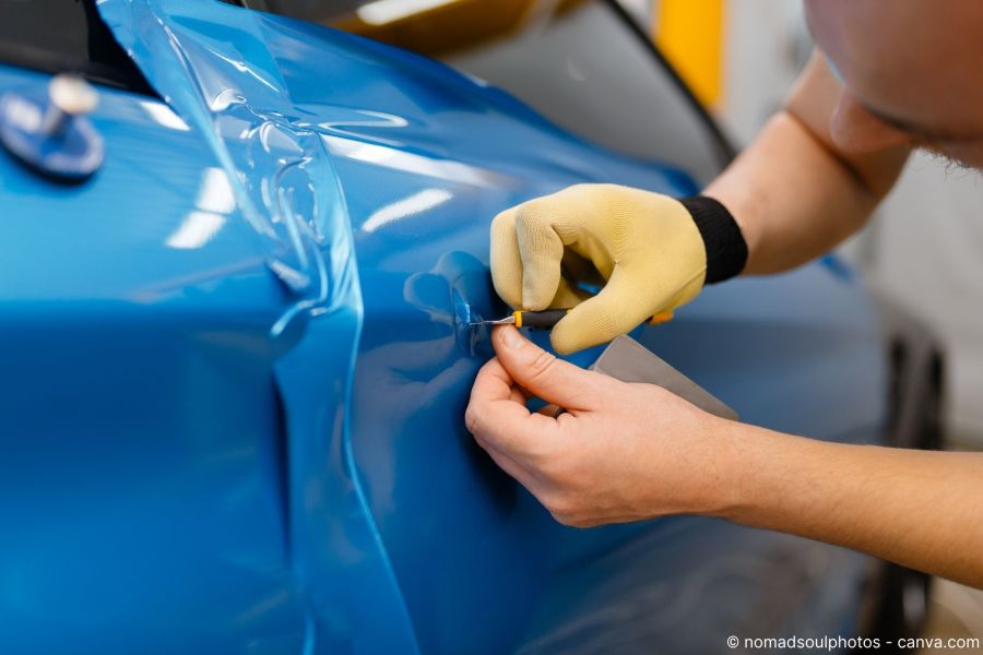 Blaue Car-Wrapping-Folie wird erhitzt, um die Kante gespannt und sauber zugeschnitten.