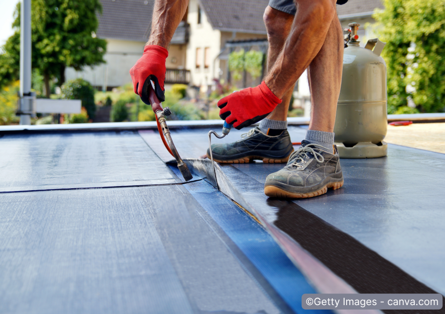 Dachdecker legt Bitumenbahnen auf Flachdach