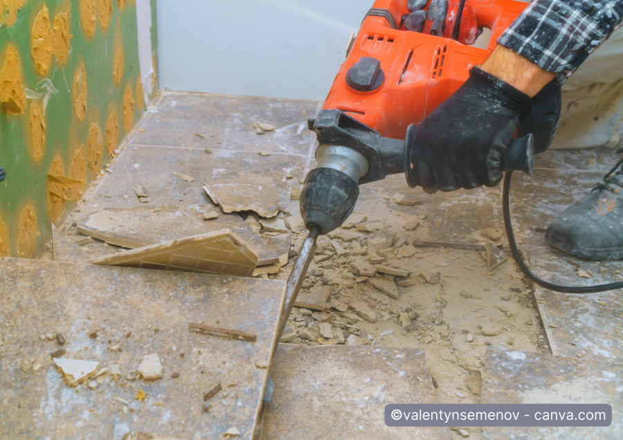Handwerker entfernt Bodenfliesen mit Bohrhammer