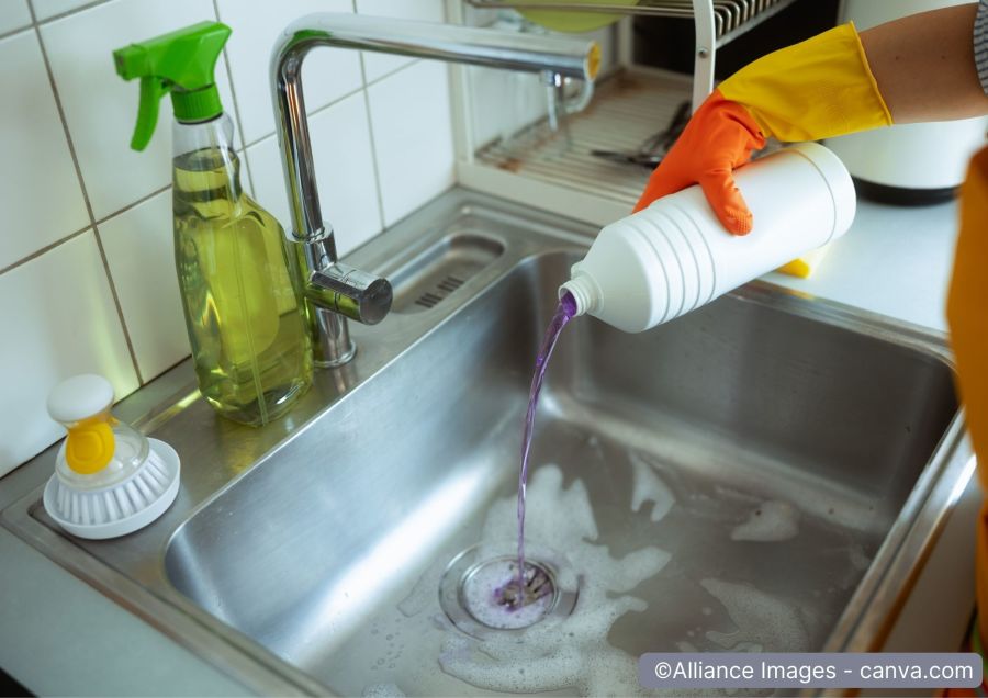 Flasche mit fluessiger Chemikalie wird in Spuele entleert