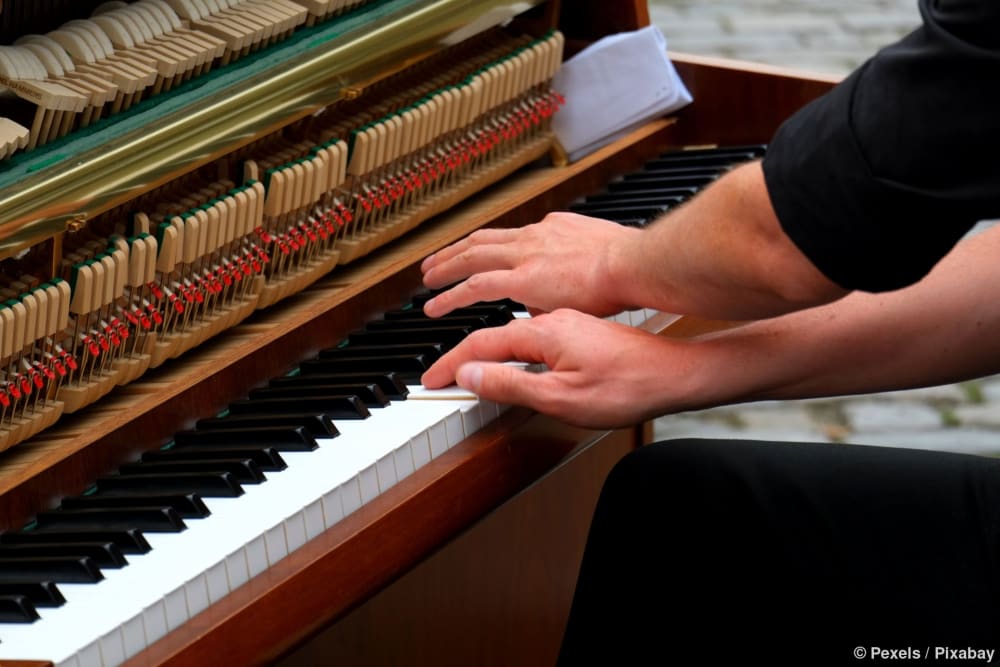 Ein Musiker prüft ein Klavier nach dem Transport, um Fehler in der Mechanik zu finden