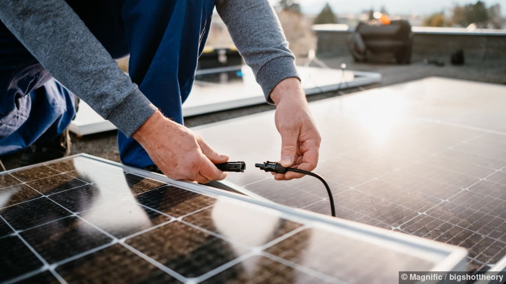 Ein Solarteur verbindet zwei Solarmodule auf einem Dach