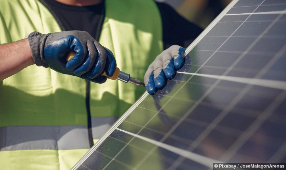 Mann installiert ein Solarmodul auf einem Dach