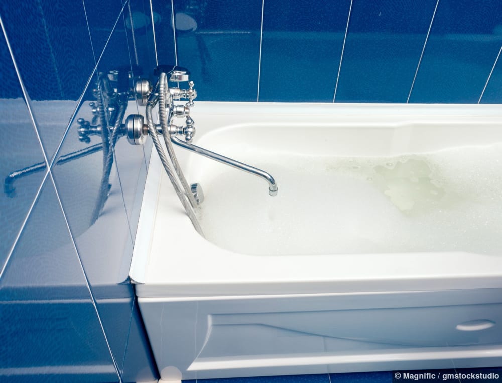 Moderne Badezimmeransicht mit einer weissen Badewanne und gefliesten Wänden