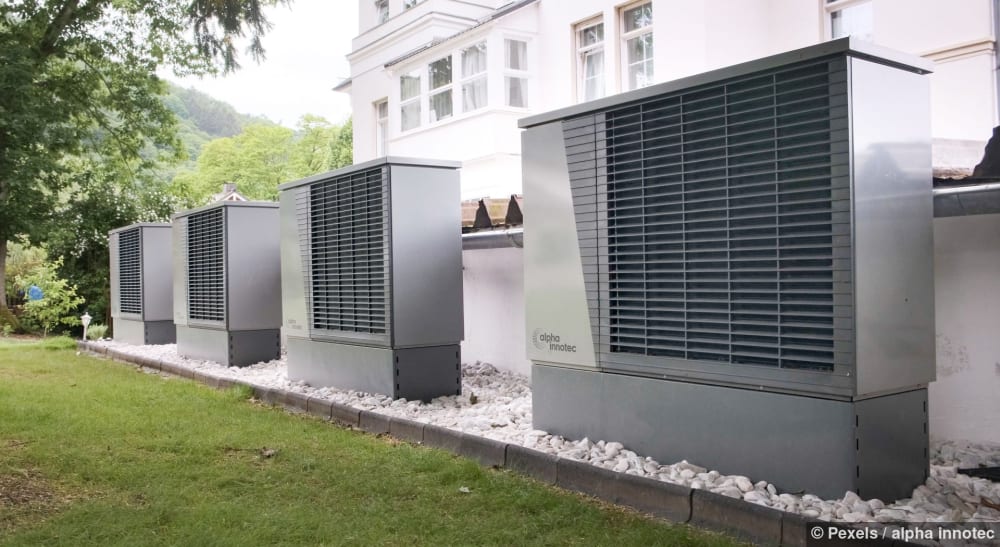 Mehrere Wärmepumpen sind vor einem Gebäude aufgestellt und werben für nachhaltige Energie