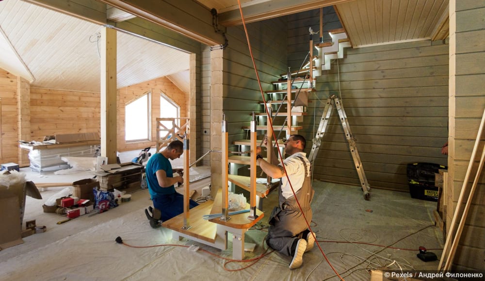 Schreiner baut eine moderne Holztreppe in einem neu errichteten Innenraum ein