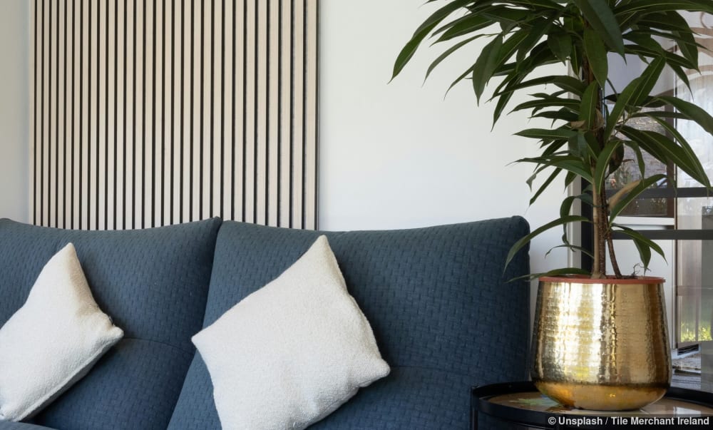 Blaues Stoffsofa und Holz-Akustikpaneel an der Wand, die zusammen die Raumakustik verbessern