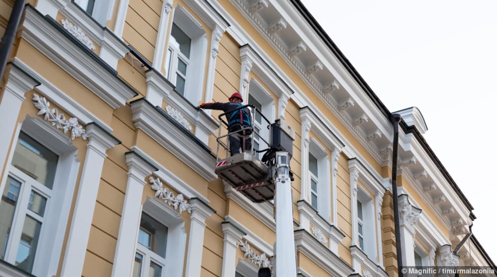 Bauarbeiter auf Hubsteiger reinigt Gebäude-Fassade