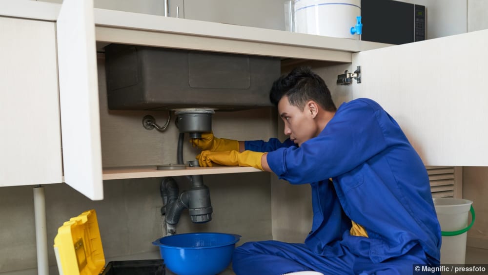 Ein Sanitärinstallateur behebt im Notfall eine Verstopfung im Abfluss