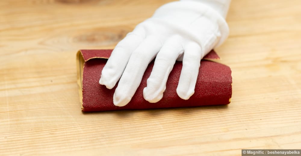 Holzoberfläche eines Parkettbodens wird mit Schleifpapier abgeschliffen