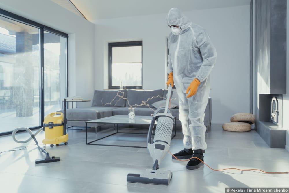Ein Reiniger in Schutzkleidung benutzt einen Staubsauger in einem modernen Zuhause