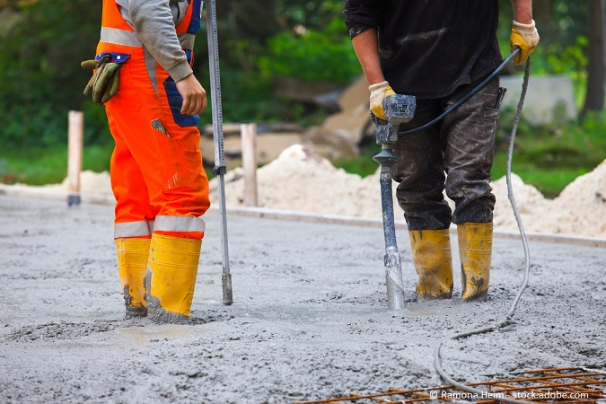 Betonfundament erstellen: Bauarbeiter verdichten Beton