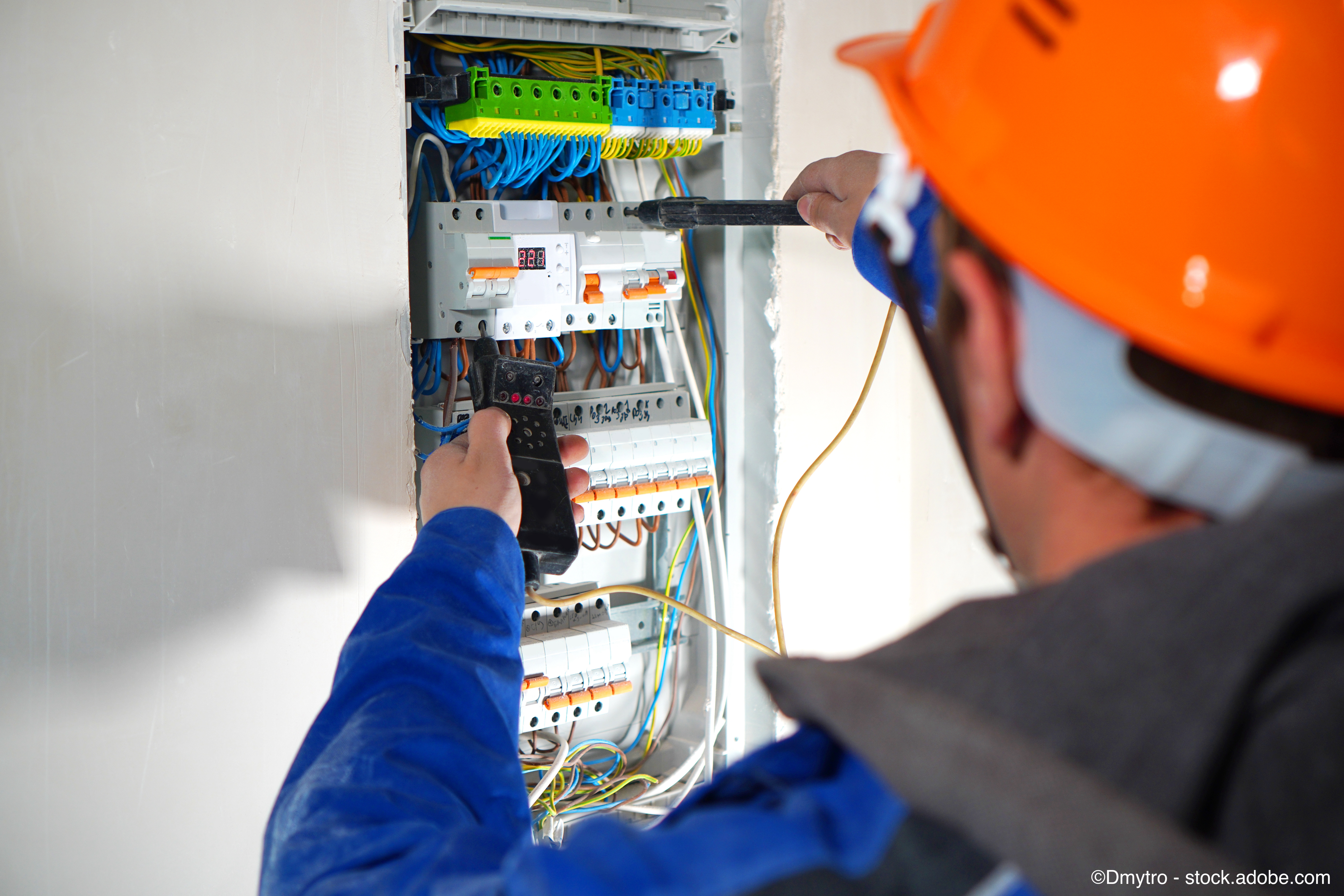 Elektriker prüft elektrische Schalttafel mit Automaten und Drähten.