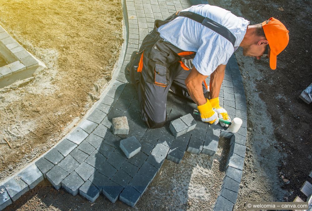 Mann-pflastert-Einfahrt-mit-Betonsteinen